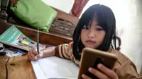 Seorang siswi memperhatikan ponsel saat belajar secara daring di Jakarta, Rabu (4/11/2020). Federasi Serikat Guru Indonesia merekomendasikan sejumlah usulan kepada Kementerian Pendidikan dan Kebudayaan untuk mengubah sistem Pembelajaran Jarak Jauh. (Liputan6.com/Faizal Fanani)