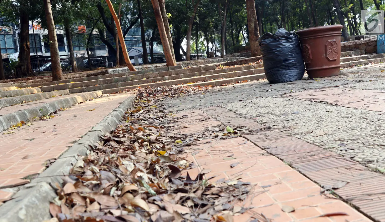 Ceceran daun kering terlihat menumpuk di area Taman Puring yang berada di kawasan Jakarta Selatan, Minggu (15/9/2019). Nampak kondisi taman memprihatinkan, sejumlah bagian taman terlihat rusak dan kotor. (Liputan6.com/Helmi Fithriansyah)