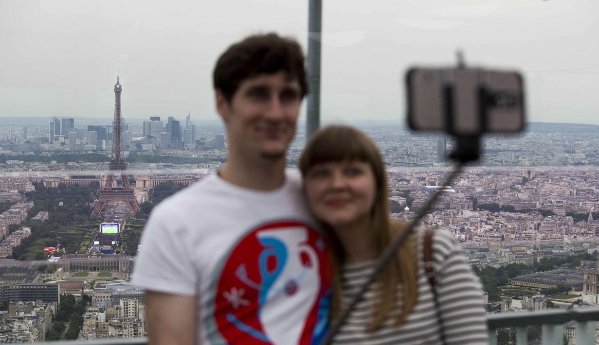 Sepasang kekasih berfoto selfie dengan background menara Eiffel sebelum menonton laga grup A  Euro 2016 antara Prancis melawan Rumania di Stade de France, Saint-Denis, (10/6/2016).  (AFP/ Geoffroy Van der Hasselt)