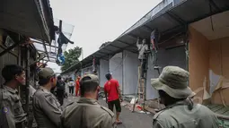 Petugas Satpol PP melihat pembongkaran kios di sepanjang Jalan Jatibaru X, Tanah Abang, Jakarta, Minggu (3/5/2015). Pembongkaran dilakukan karena kios tersebut menutupi saluran air sehingga menyebabkan saluran air mampet. (Liputan6.com/Faizal Fanani)