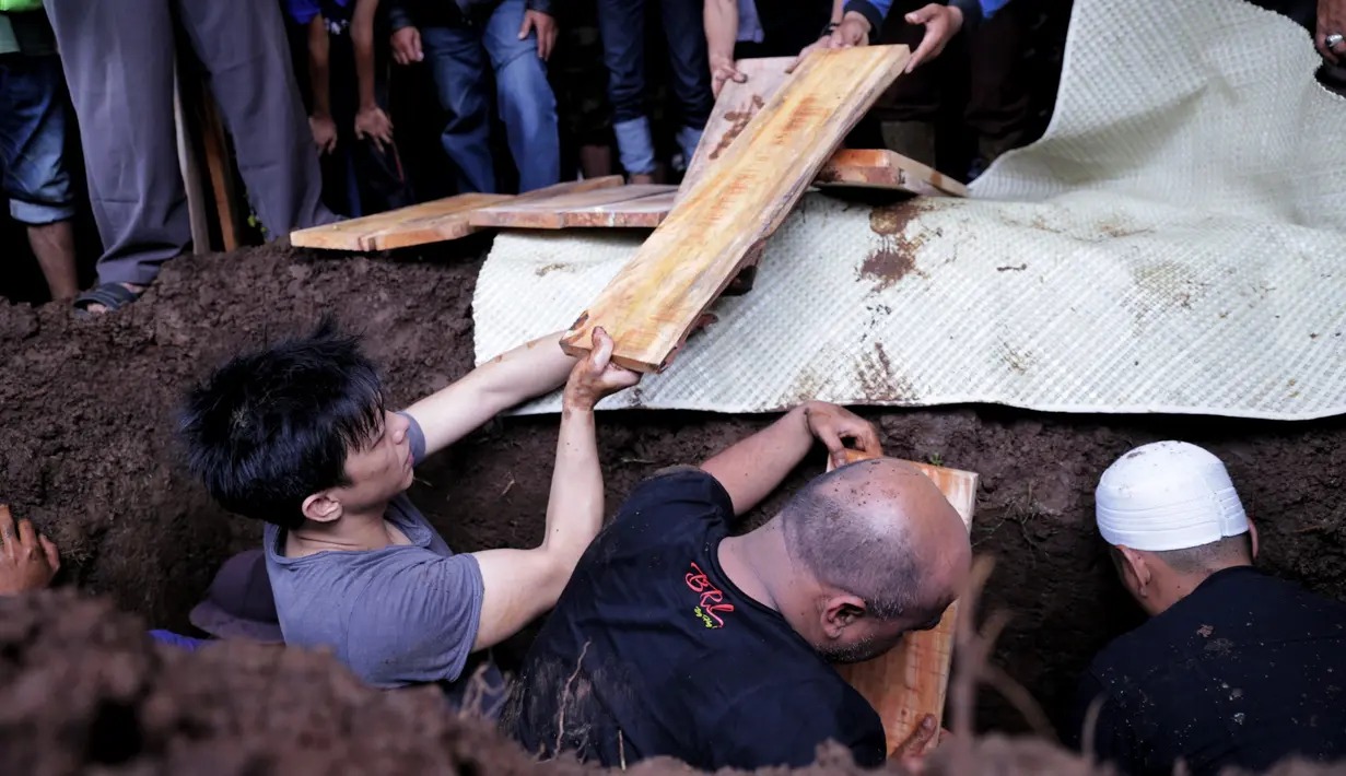 Ariel menerima papan untuk menutupi jenazah yang hendak diurug dengan tanah. (Adrian Putra/Bintang.com)