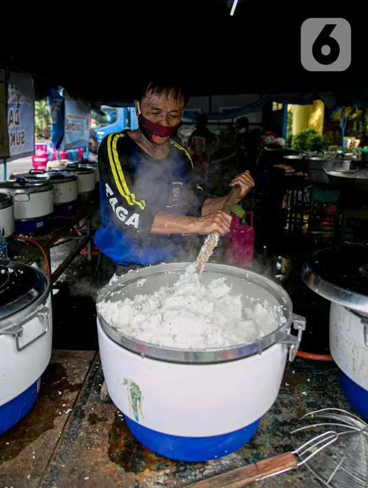 Petugas Taruna Siaga Bencana (Tagana) memasak nasi di Dapur Umum Kementerian Sosial di GOR Otista, Jakarta, Minggu (21/2/2021). Dalam sehari, petugas menyiapkan hingga 6.000 paket nasi kotak yang didistribusikan ke 11 kelurahan terdampak banjir. (Liputan6.com/Faizal Fanani)