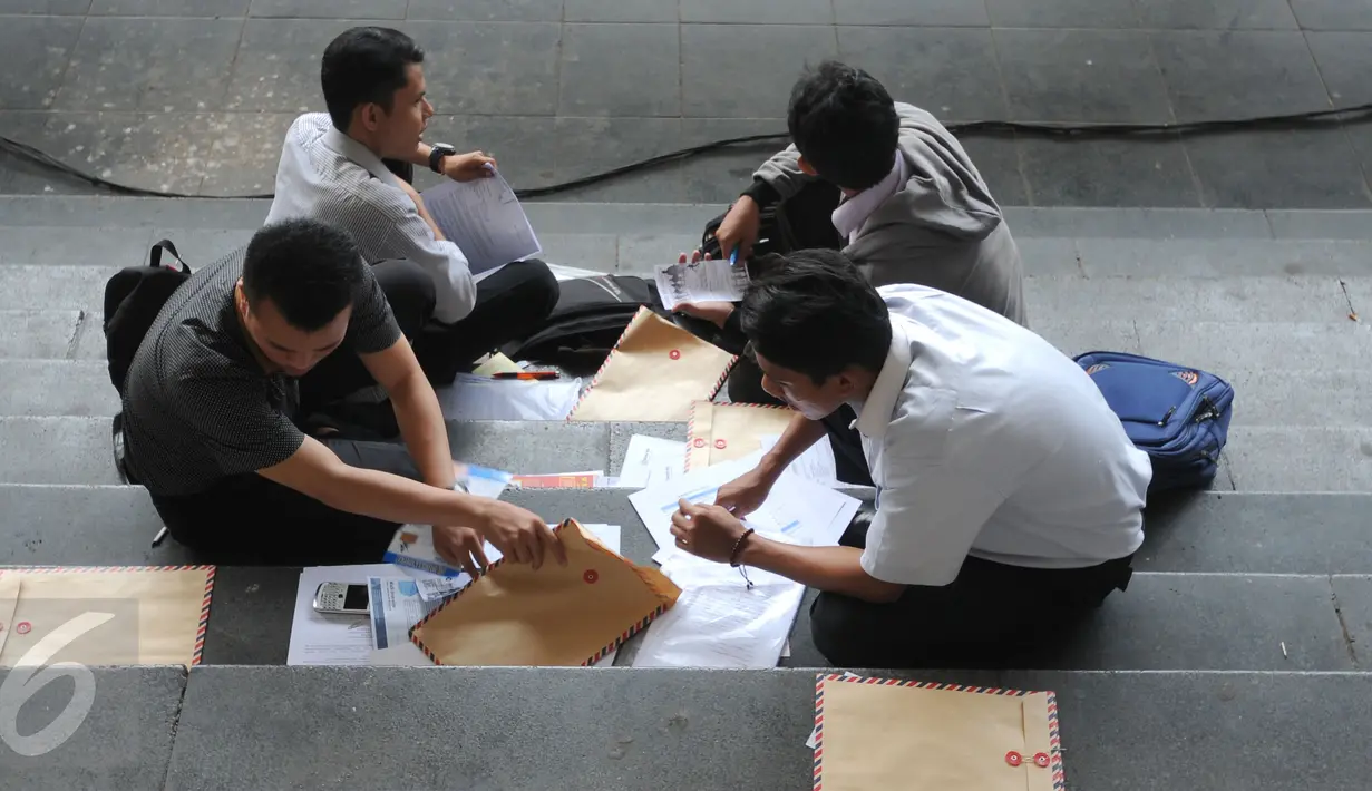 Sejumlah pelamar menyiapkan berkas saat menghadiri Job for Career di Stadion Gelora Bung Karno Jakarta, Rabu (30/9/2015). Tingginya angka pencari kerja menjadikan bursa kerja ramai peminat. (Liputan6.com/Helmi Fithriansyah)