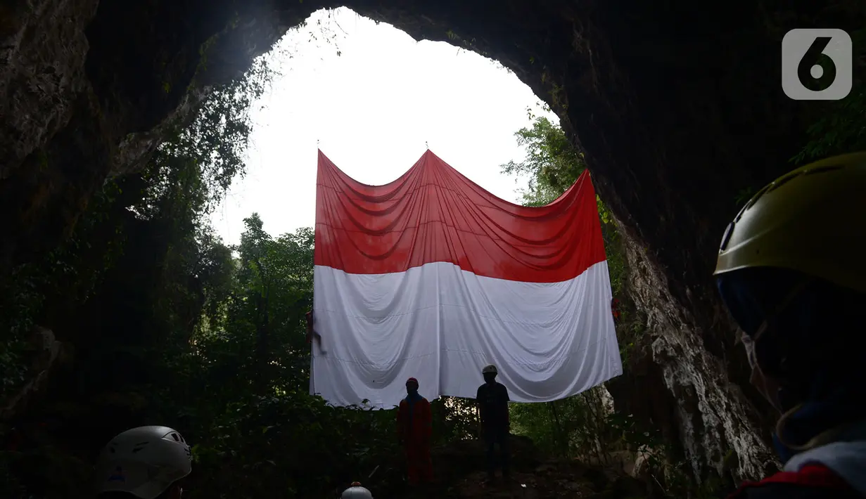 Jaringan Masyarakat Peduli Karst Klapanunggal membentangkan bendera merah putih dalam rangka peringatan HUT ke-75 RI di Tebing Kutalingkung, Klapa Nunggal, Jawa Barat, Senin (17/8/2020). Sebanyak 80 orang mengikuti pengibaran bendera berukuran 15 meter x 10 meter tersebut. (merdeka.com/Imam Buhori)