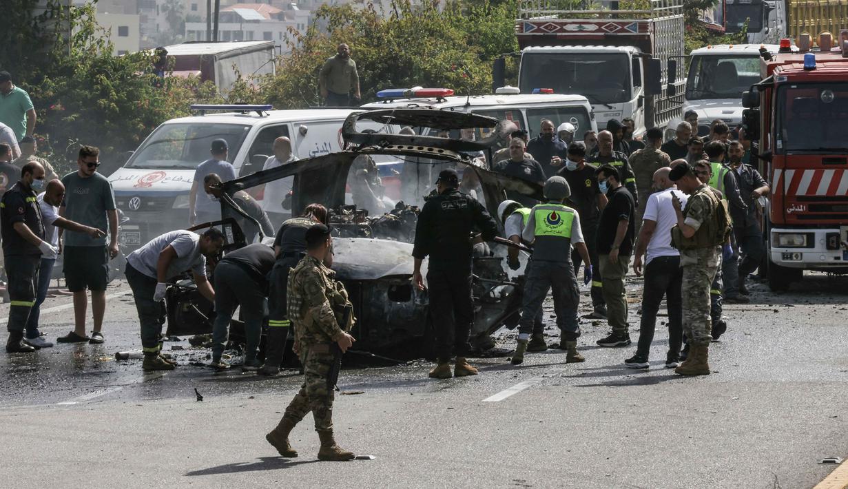 Petugas tanggap darurat bekerja di sekitar kendaraan yang menjadi sasaran serangan pesawat tak berawak Israel di jalan raya dekat kota Jiyeh, Selatan Beirut, pada Rabu 13 Mei 2026. (MAHMOUD ZAYYAT/AFP)