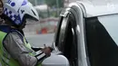 Polisi memberikan surat tilang kepada pengemudi mobil yang melanggar sistem ganjil genap di Jalan MT Haryono, Jakarta, Rabu (1/8). Hari pertama pemberlakuan sistem ganjil genap, pelanggar dikenakan sanksi Rp 500 ribu. (Merdeka.com/Iqbal S. Nugroho)