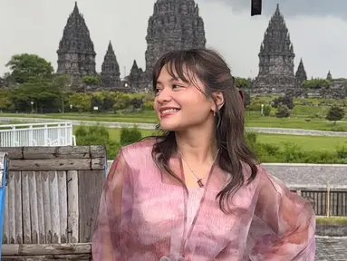 Amel Carla tampil anggun dalam balutan kebaya modern berwarna pastel. Latar belakang Candi Prambanan menambah kesan dramatis pada foto tersebut. Rambutnya dibiarkan terurai dengan gaya wavy natural, dipadukan dengan riasan natural. (Liputan6.com/IG/@amelcarla)