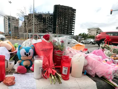 Foto ini menunjukkan bunga dan lilin yang diletakkan di trotoar setelah kebakaran besar menewaskan sepuluh orang di sebuah blok perumahan bertingkat di Valencia pada 26 Februari 2024. (Mao/AFP)