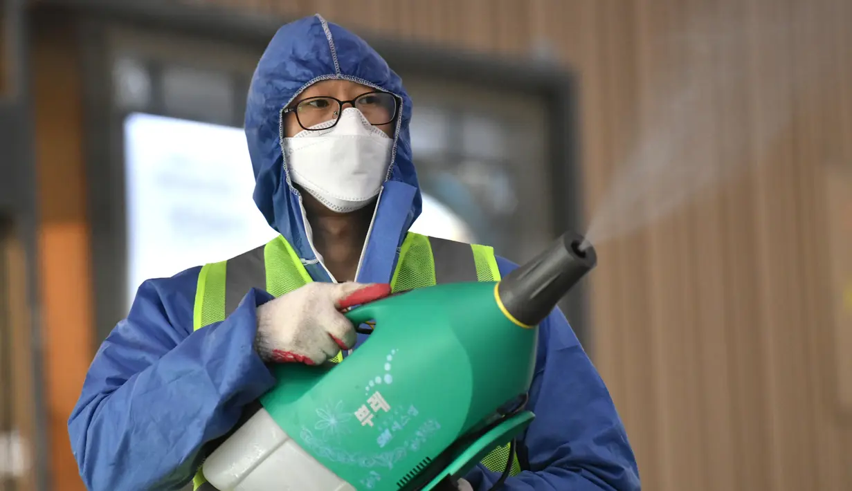 Seorang pekerja mengenakan pakaian pelindung saat menyemprotkan Disinfektan sebagai tindakan pencegahan virus corona COVID-19 di sebuah stasiun kereta api di Daegu, Korea Selatan  (26/2/2020). Jumlah korban virus corona di Korea Selatan dilaporkan menjadi 10 orang. (AFP Photo/Jung Yeon-je)