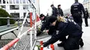 Polisi Jerman mengatur bunga yang dibawa oleh orang-orang di depan Kedutaan Besar Prancis di Berlin, Sabtu (14/11/2015). Karangan bunga tersebut untuk menghormati para korban serangan mematikan di Paris. (AFP Photo/ Tobias Schwarz)