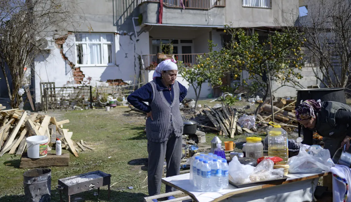 Seorang penduduk berdiri di depan rumahnya yang hancur di Samandag, selatan Hatay pada 16 Februari 2023, sepuluh hari setelah gempa berkekuatan 7,8 melanda wilayah perbatasan Turki dan Suriah. Banyak orang di kota Samandag di wilayah perbatasan Suriah mendengarkan kerabat dan teman mereka perlahan-lahan mati di bawah reruntuhan saat mereka menunggu penyelamat yang datang terlambat. (Photo by Yasin AKGUL / AFP)
