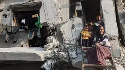 Bantuan ini merupakan bagian dari rencana tanggap darurat 60 hari di tengah meningkatnya serangan militer Israel di wilayah tersebut. Tampak dalam foto, sebuah keluarga Palestina memandang ke bawah dari rumah mereka yang rusak parah di Jabalia, di bagian utara Jalur Gaza, pada Jumat 7 November 2025. (Omar AL-QATTAA/AFP)