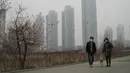 Warga dan anjingya memakai masker saat jalan-jalan akibat polusi udara yang menyelimuti Seoul, Korea Selatan, 15 Maret 2019. Tujuh kota besar di Korea Selatan menderita konsentrasi tinggi partikel PM 2,5 yang berbahaya. (REUTERS/Hyun Young Yi)