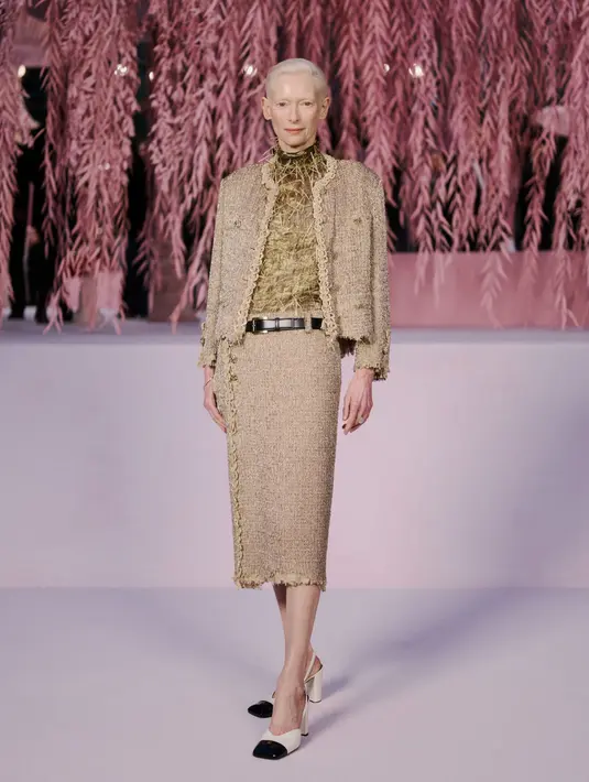 Aktris Tilda Swinton tak kalah menawan dengan turtleneck keemasan berbalut tweed blazer. Dipadu dengan tweed midi skirt dan square heels Chanel [Chanel]