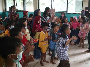 Direktur PAUD Institute Danang Sasongko (kiri) dan karyawan Askrindo menghibur anak-anak korban banjir dengan bermain, bernyanyi dan menari bersama di Kantor Kecamatan Cilamaya Wetan, Cikampek Jumat (12/02/2021). (Liputan6.com/Pool/Askrindo)