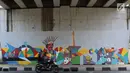 Pengendara motor melintas di samping mural bertema Asian Games 2018 di kolong flyover Universitas Indonesia, Depok, Jawa Barat, Jumat (27/7). Perhelatan Asian Games 2018 akan berlangsung di Jakarta dan Palembang. (Liputan6.com/Immanuel Antonius)