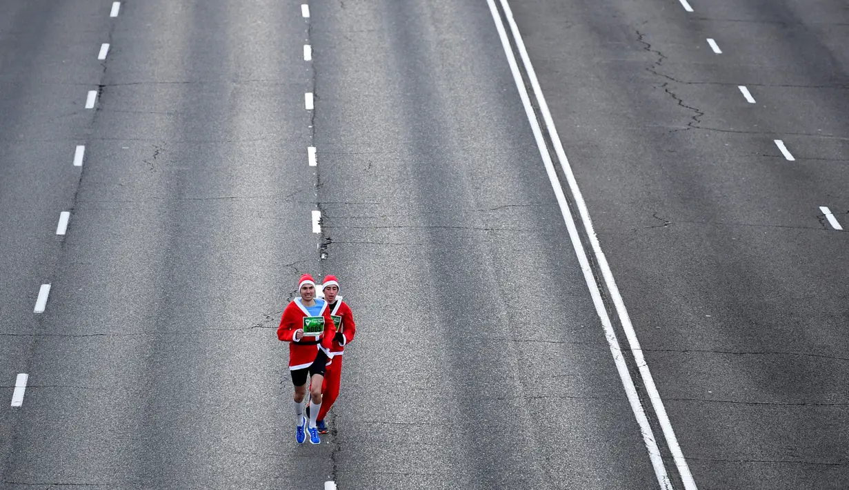 Pelari mengenakan kostum Sinterklas ambil bagian dalam Santa Claus Run di Madrid, Spanyol, Minggu (9/12). Ribuan orang berjalan dan berlari dalam perlombaan Santa tahunan melintasi jalan-jalan ibu kota Spanyol. (Gabriel BOUYS / AFP)