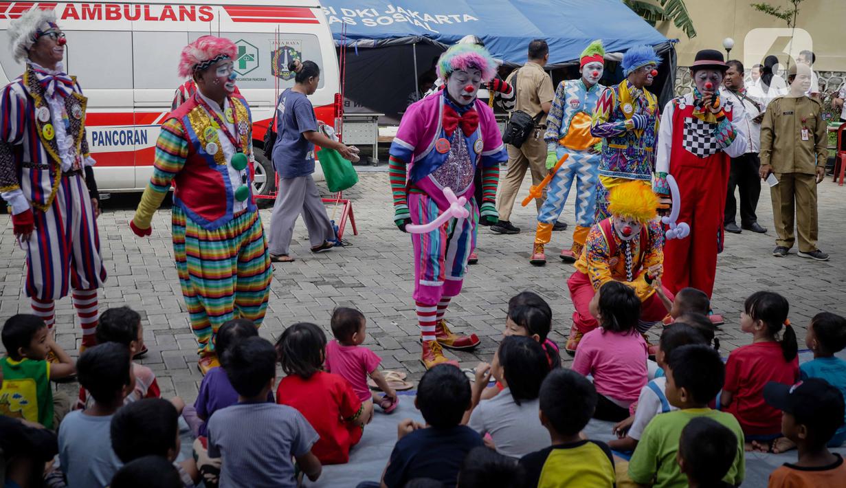 Anak-anak menyaksikan aksi badut yang tergabung dalam komunitas Aku Badut Indonesia (ABI) di pengungsian korban banjir di Gor Pangadegan, Jakarta, Selasa (7/1/2020). Trauma healing diberikan para badut sebagai bentuk kepedulian terhadap anak-anak korban banjir Jakarta. (Liputan6.com/Faizal Fanani)