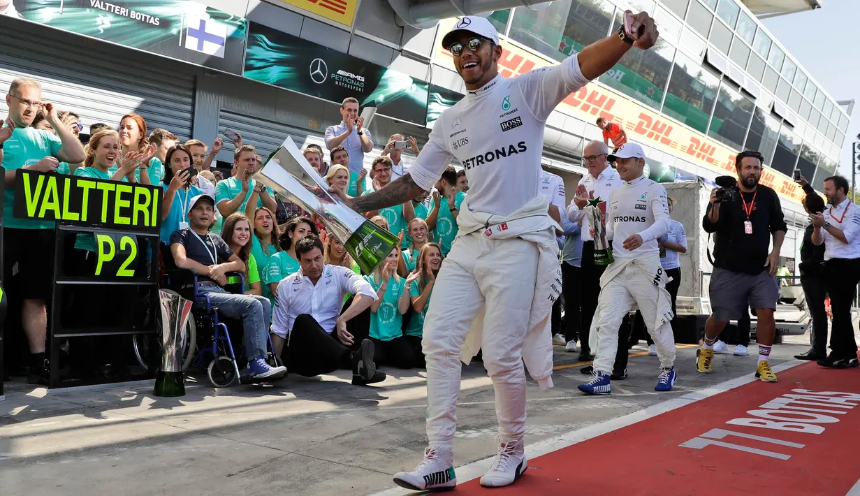Lewis Hamilton merayakan kemenangannya dalam balapan F1 GP Italia, di arena Monza, Italia (3/9). Hamilton keluar sebagai juara pada balapan F1 GP Italia dengan keunggulan 4,4 detik atas Valtteri Bottas yang finis kedua. (AP Photo/Luca Bruno)