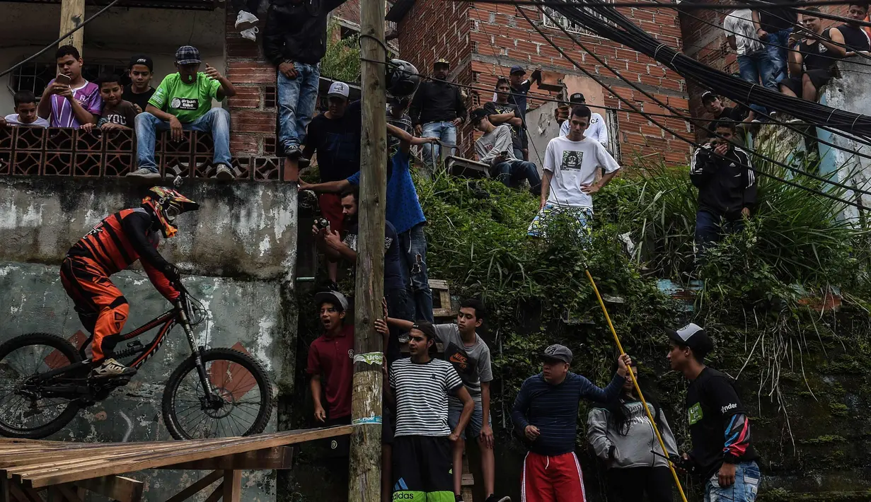 Warga menyaksikan pengendara sepeda mengayuh sepedanya saat mengikuti balapan Urban Bike Inder Medellin di gubuk comuna 1 di Medellin, Antioquia department, Kolombia (19/11). (AFP Photo/Joaquin Sarmiento)