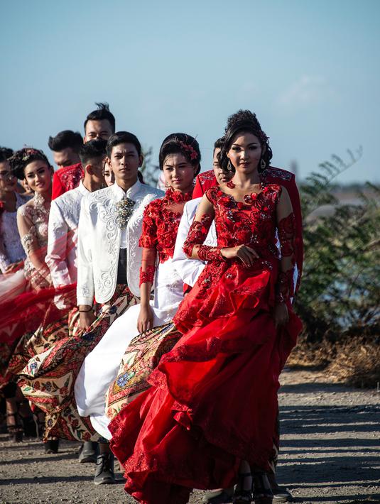 Model dengan balutan busana tradisional berlenggak-lenggok saat fashion show di tanggul Lapindo Porong, Sidoarjo, Jawa Timur, Selasa (13/8/2019). Sebanyak 15 model menunjukkan mode busana yang didominasi warna merah dan putihdalam acara tersebut. (Photo by JUNI KRISWANTO / AFP)