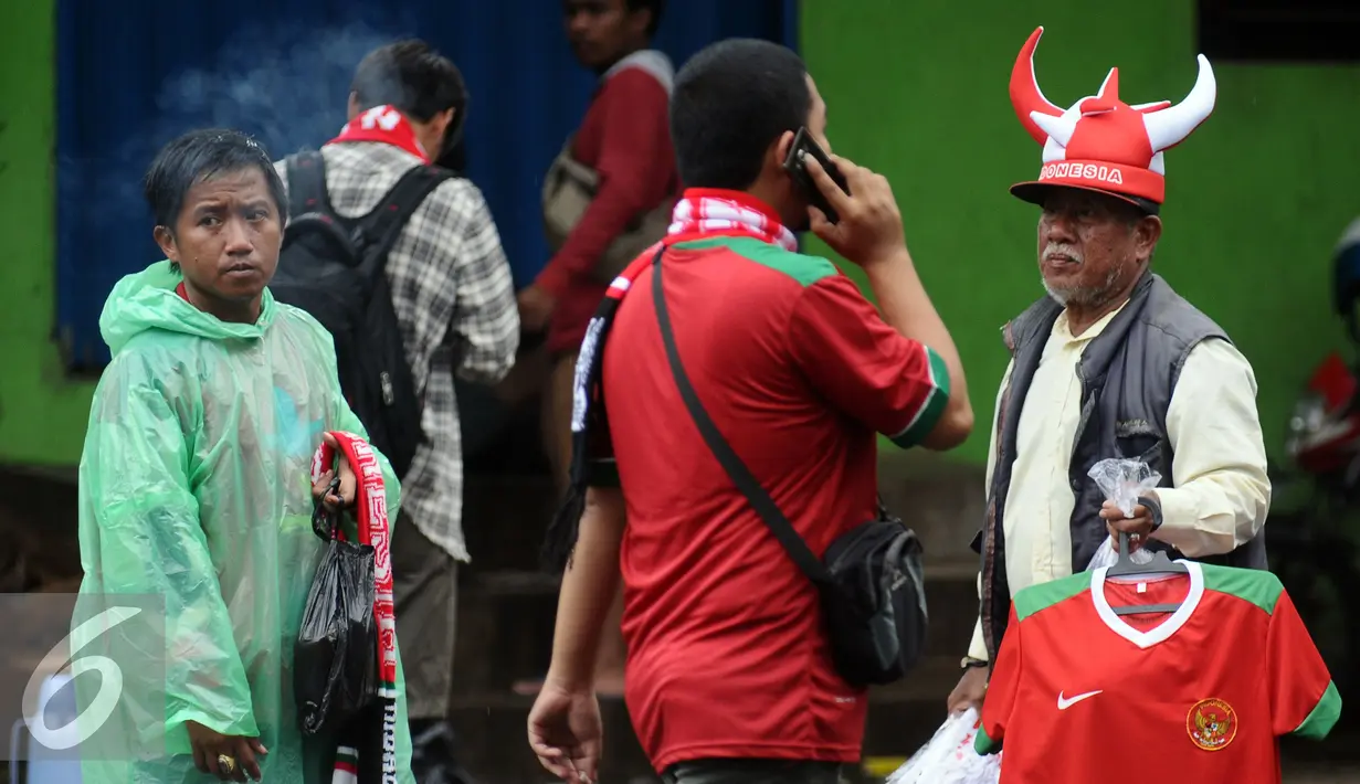 Pedagang menawarkan kaos kepada suporter Timnas Indonesia di sekitar Stadion Pakansari, Bogor, Sabtu (3/12). Timnas Indonesia akan melakoni laga semifinal pertama Piala AFF 2016 melawan Vietnam. (Liputan6.com/Helmi Fithriansyah)