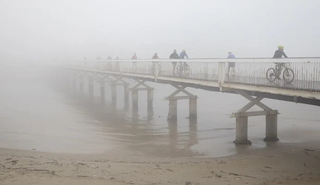 Sejumlah pengendara sepeda menyeberangi jembatan saat hari berkabut di Tel Aviv, Israel, Rabu (6/1/2021). Kabut yang cukup tebal tersebut disebabkan oleh udara yang mengalir ke darat dari laut, menyebabkan kelembaban meningkat di dataran pantai dan daerah lainnya. (AP Photo/Oded Balilty)