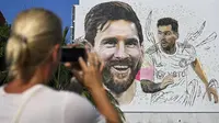 Seorang wanita memotret mural besar bergambar Lionel Messi di Wynwood, Miami, 10 Juli 2023. La Pulga akan melakukan debutnya di Inter Miami pada 21 Juli di Piala Liga. (AFP/Chandan Khanna)