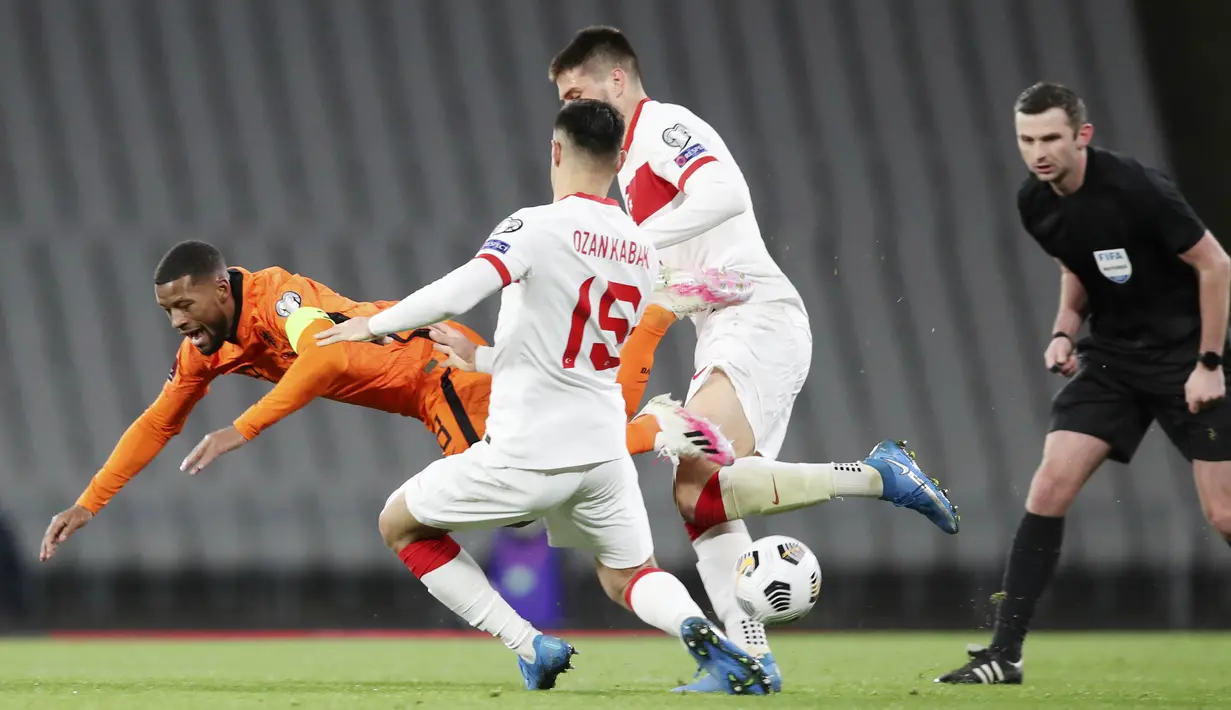 Gelandang Belanda, Georginio Wijnaldum, terjatuh saat berebut bola dengan bek Turki, Ozan kabak, pada laga kualifikasi Piala Dunia 2022 di Stadion Olimpiade Ataturk, Kamis (25/3/2021). Turki menang dengan skor 4-2. (Tolga Bozoglu/Pool Photo via AP)