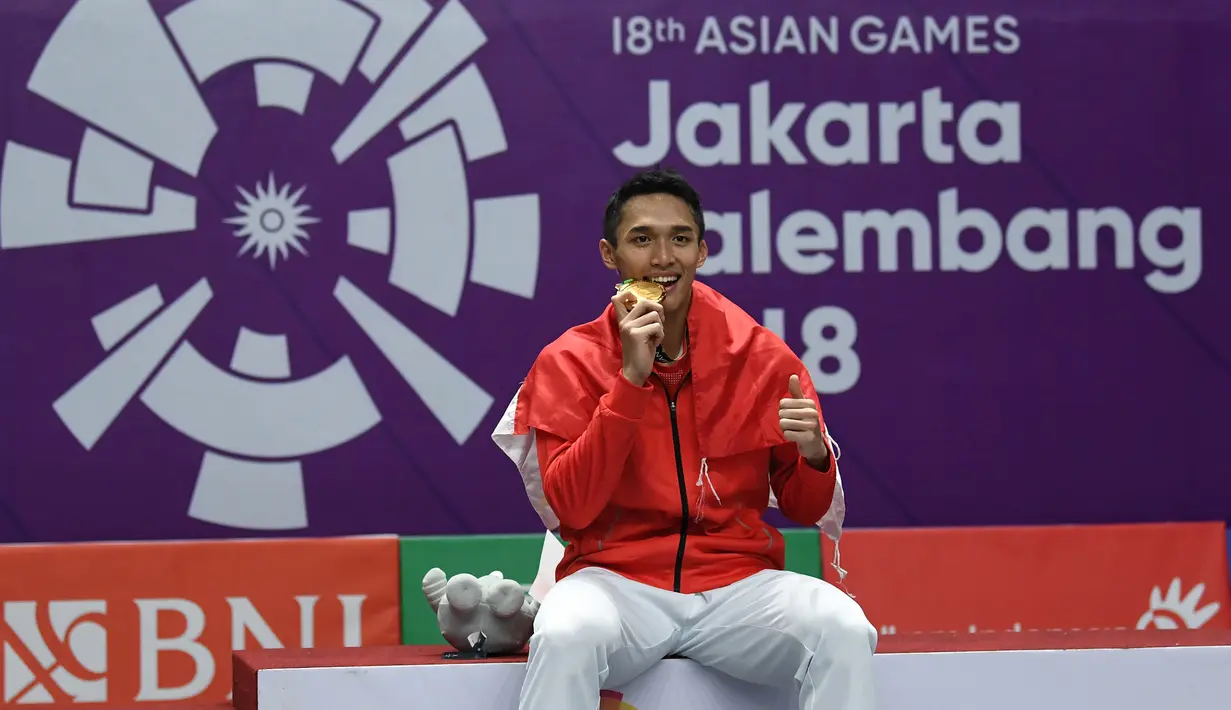 Pebulu tangkis Indonesia, Jonatan Christie mengigit medali emas usai upacara penghargaan cabang olahraga badminton Asian Games 2018 di Jakarta, Selasa (28/8). Jonatan menang atas wakil Chinese Taipei, Chou Tienchen.  (AFP Photo/Sonny Tumbelaka)