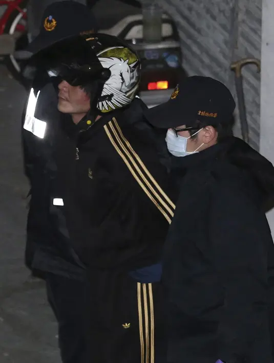 Seorang pria (tengah) diamankan polisi ke Pusat Penahanan Taipei, Taiwan, Selasa (29/3). Pria itu memenggal kepala bocah tiga tahun dengan menggunakan pisau daging di dekat stasiun metro di Taipei, pada 28 Maret kemarin. (REUTERS/Tony HuangTAIWAN OUT)