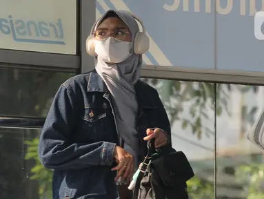 Seorang wanita mengenakan masker berada di halte Transjakarta di Kawasan Velodrome Jakarta Timur, Jumat (28/7/2023). (merdeka.com/imam buhori)