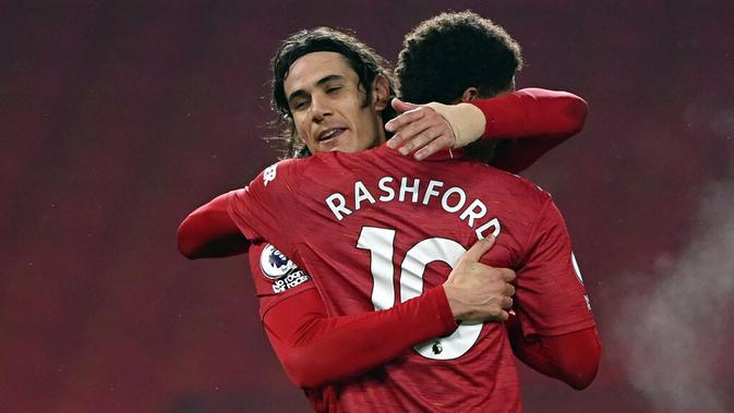 Striker Manchester United, Edinson Cavani, melakukan selebrasi bersama Marcus Rashford usai mencetak gol ke gawang Southampton pada laga Liga Inggris di Stadion Old Trafford, Selasa (2/2/2021). Setan Merah menang dengan skor 9-0. (Laurence Griffiths/Pool via AP)