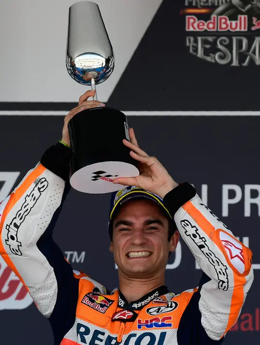 Pembalap Repsol Honda, Dani Pedrosa memegang trofi saat merayakan kemenangannya (kanan) pada balapan MotoGP Spanyol di Sirkuit Jerez, Minggu (7/5). Pedrosa finish terdepan dengan catatan waktu 45 menit 26,827 detik. (PIERRE-PHILIPPE MARCOU / AFP)