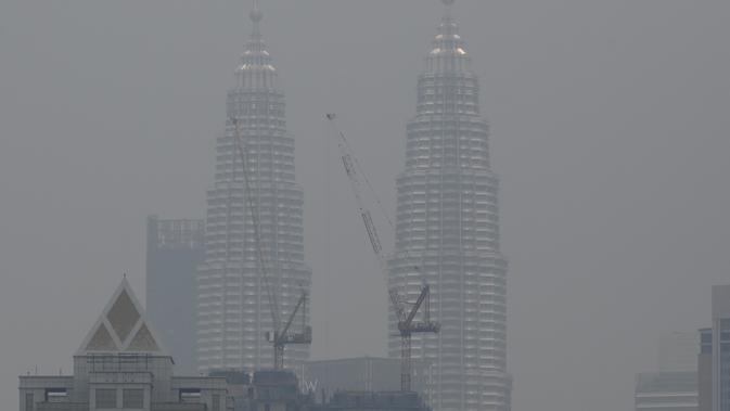 Menara Kembar Petronas diselimuti kabut asap di Kuala Lumpur, Malaysia (10/9/2019). Departemen Pendidikan Kota Sarawak, Malaysia meminta sekolah-sekolah ditutup sementara menyusul memburuknya udara akibat kabut asap kebakaran hutan di wilayah itu. (AFP Photo/Mohd Rasfan)