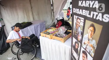 Penyandang disabilitas menjaga booth pada acara puncak peringatan Hari Disabilitas Internasional 2019 di Plaza Barat Gelora Bung Karno, Jakarta, Selasa (3/12/2019). Acara ini mengangkat tema 'Indonesia Inklusi, Disabilitas Unggul'. (Liputan6.com/Faizal Fanani)