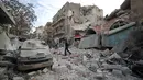Warga berjalan melewati puing-puing bangunan setelah serangan udara rezim di Kota Ariha, Idlib, Suriah, Rabu (15/1/2020). Pada 9 Januari, gencatan senjata di Idlib dideklarasikan dengan inisiatif Rusia dan Turki. (Omar HAJ KADOUR/AFP)