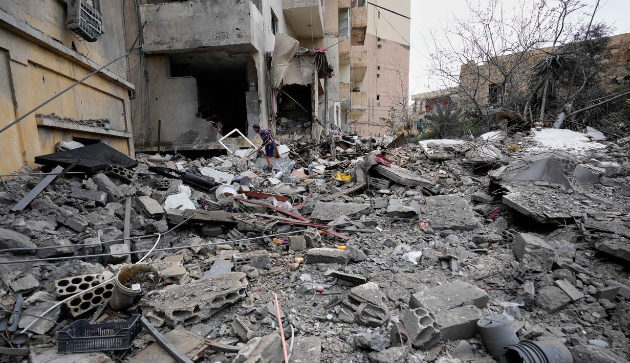 Serangan udara dan artileri Israel terus menargetkan infrastruktur yang diklaim sebagai milik kelompok Hizbullah yang berdampak signifikan pada warga sipil dan fasilitas publik. Tampak dalam foto, seorang pria menyingkirkan puing-puing sambil mencari barang-barang yang hilang dari rumahnya yang hancur akibat serangan udara Israel di kota pelabuhan Tyre, Lebanon selatan, Kamis, 26 Maret 2026. (AP Photo/Hussein Malla)