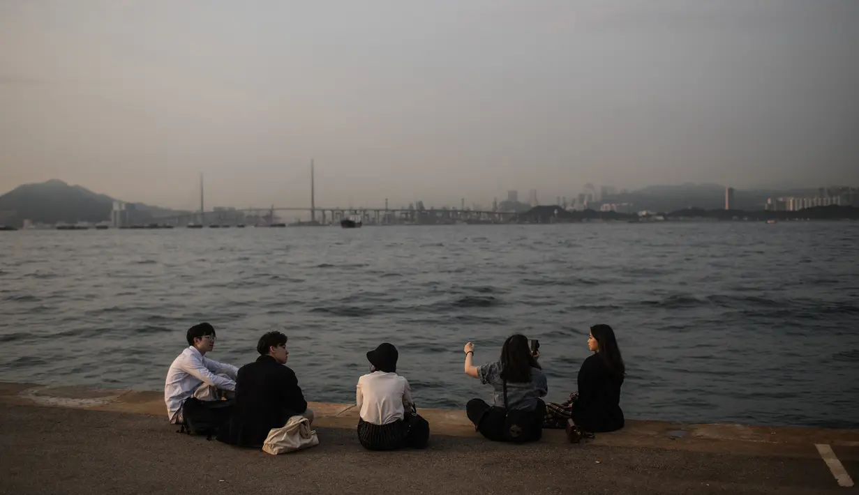 Orang-orang mengobrol di dermaga umum di sebelah Pelabuhan Victoria di Hong Kong (3/3). Pelabuhan ini merupakan tempat berkumpul yang populer bagi para turis dan penduduk. (AFP Photo/Dale De La Rey)