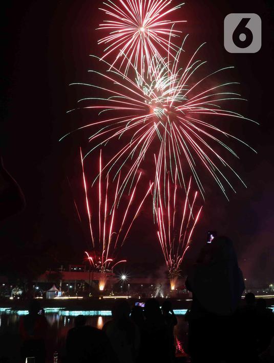 Warga menyaksikan pesta kembang api saat perayaan malam puncak Tahun Baru 2023 di Danau Archipelago, Taman Mini Indonesia Indah (TMII), Jakarta, Minggu (1/1/2023). Danau Archipelago TMII menjadi pusat pesta kembang api di malam tahun baru 2023. (Liputan6.com/Herman Zakharia)