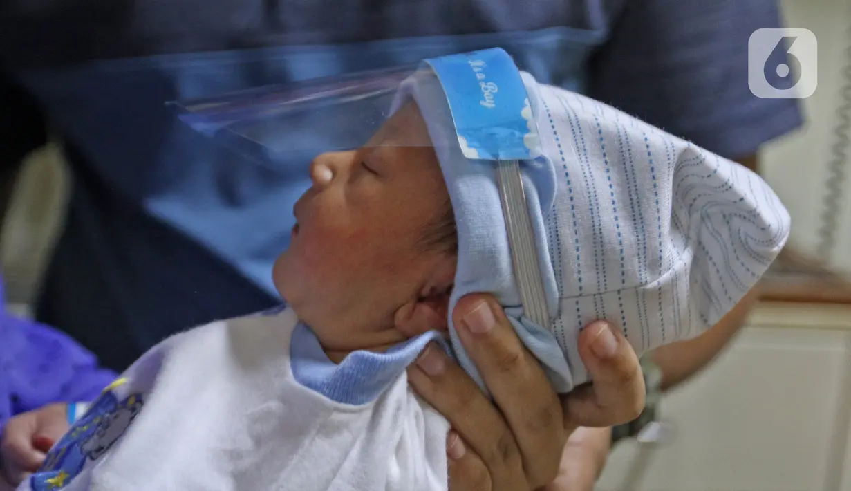 Seorang bayi memakai face shield atau pelindung wajah di Rumah Sakit Ibu dan Anak Tambak, Jakarta, Selasa (14/4/2020). RSIA Tambak sejak 12 April 2020 membuat kebijakan bayi yang baru lahir dipakaikan pelindung wajah untuk mencegah terpapar virus corona COVID-19. (Liputan6.com/Herman Zakharia)
