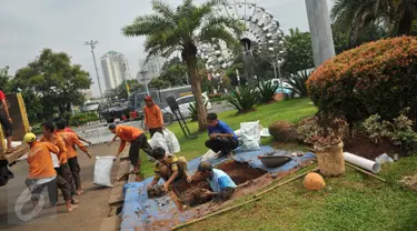 Pekerja mengangkut tanah saat pembuatan sumur resapan di Monas, Jakarta, Jumat (22/7). Pembuatan puluhan sumur resapan itu guna mengantisipasi genangan air hujan dan menyimpan air di Kawasan Monas dan depan Istana Merdeka. (Liputan6.com/Gempur M Surya)