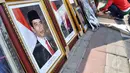 Pedagang memasukkan foto resmi kenegaraan Presiden Joko Widodo atau Jokowi dan Wakil Presiden Jusuf Kalla ke dalam pigura di Pasar Baru, Jakarta, Sabtu (25/10/2014). (Liputan6.com/Miftahul Hayat)