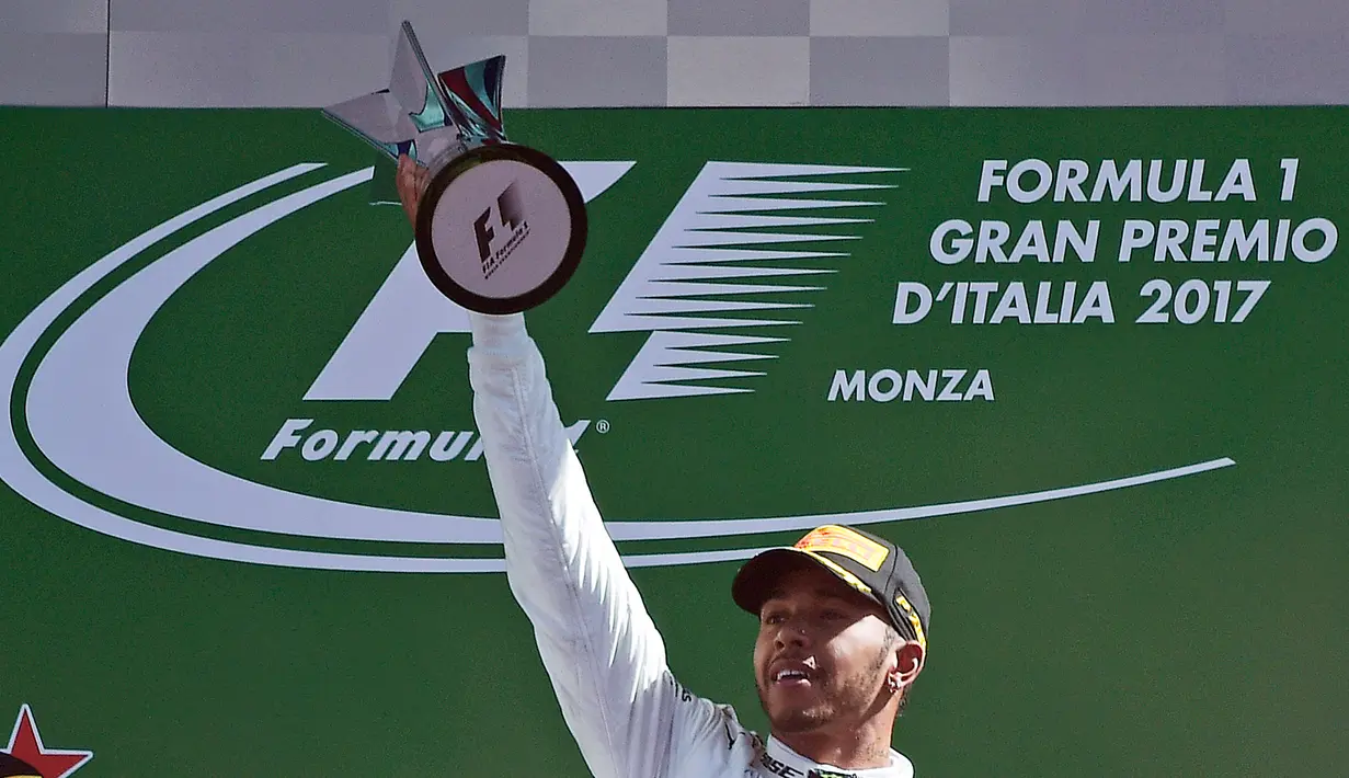 Pembalap Mercedes Lewis Hamilton mengangkat trofi usai memenangkan balapan F1 GP Italia, di arena Monza, Italia (3/9). (AFP Photo/Miguel Medina)