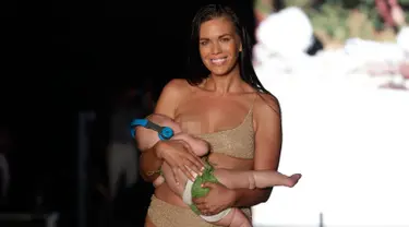 Model Mara Martin berjalan di atas runway sambil menyusui bayinya mengenakan pakaian renang Sports Illustrated pada Miami Swim Week 2018 di Florida, Minggu (15/8). Mara adalah salah satu finalis yang terpilih untuk tampil pada acara itu. (AP/Lynne Sladky)