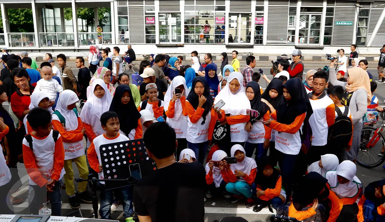 Sejumlah anak yang tergabung dalam Rumah Amalia Ciledug melihat aksi musik grup band di Jalan MH Thamrin, Jakarta (07/02). Kegiatan tersebut dalam rangka meciptakan rasa aman dan perdamaian paska bom Thamrin. (Liputan6.com/Fery Pradolo)