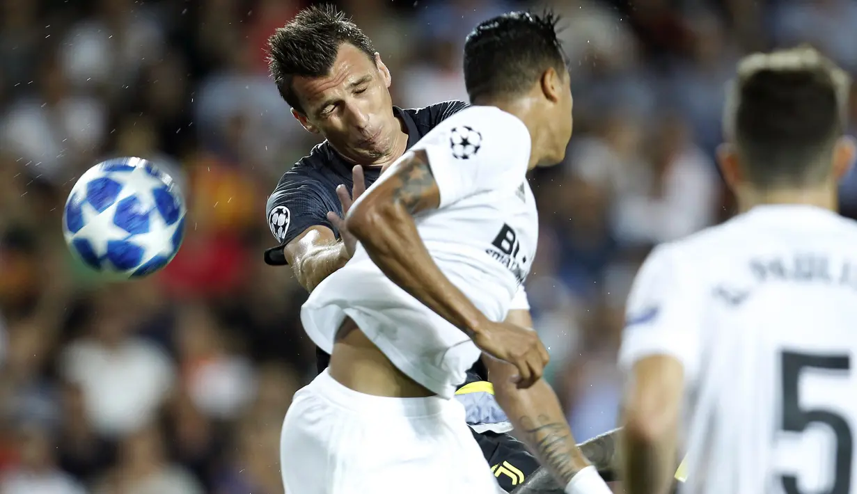 Striker Juventus, Mario Mandzukic, duel udara dengan bek Valencia, Jeison Murillo, pada laga Liga Champions di Stadion Mestalla, Valencia, Rabu (19/9/2018). Juventus menang 2-0 atas Valencia. (AP/Alberto Saiz)