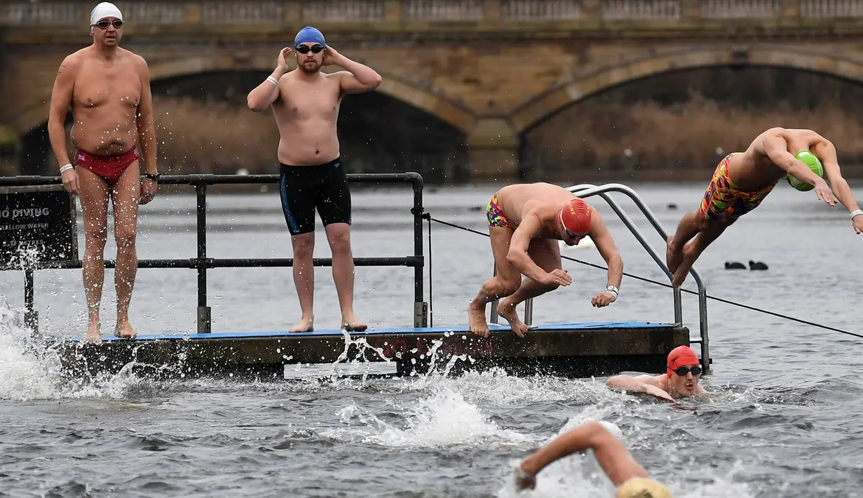 Peserta meluncur ke danau saat mengikuti lomba berenang di Danau Serpentine di Hyde Park, London, Inggris, Minggu (25/12). Lomba berenang di danau yang dingin ini sudah menjadi acara tahunan setiap perayaan natal. (REUTERS/Toby Melville)