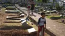 Anak-anak bermain di sekitar Taman Pemakaman Umum (TPU) Karet Bivak, Jakarta, Selasa (10/9/2019). Keterbatasan ruang terbuka hijau memaksa sebagian anak-anak di Ibu Kota bermain tidak pada tempatnya, meskipun dalam kondisi yang tidak layak. (Liputan6.com/Immanuel Antonius)