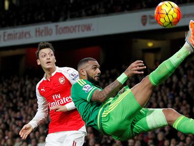 Pemain Arsenal, Mesut Ozil (kiri) melihat gelandang Sunderland, Yann M'vila, saat menendang salto dalam laga Liga Inggris di Stadion Emirates, London, (5/12/2015). (AFP/IKIMAGES/Ian Kington) 